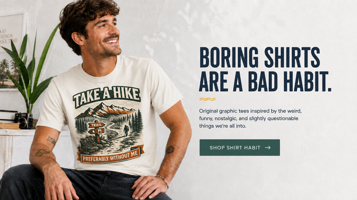 A man wearing a cream graphic t-shirt with a vintage-style mountain and forest design and the text 'TAKE A HIKE PREFERABLY WITHOUT ME'. The image is a promotional ad with text on the right reading 'BORING SHIRTS ARE A BAD HABIT.