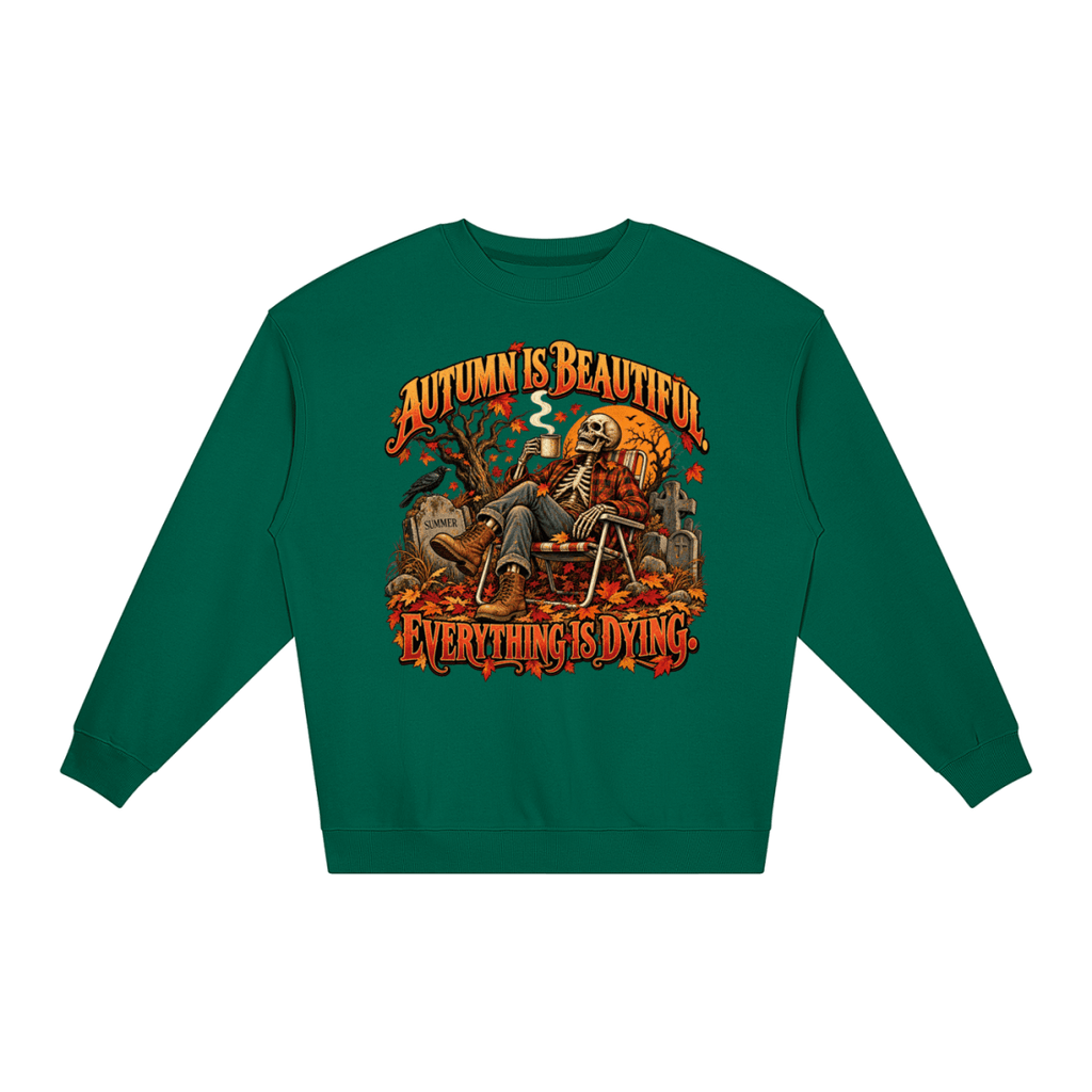 Green Autumn Is Beautiful Everything Is Dying loose crewneck sweatshirt, front view with a seated skeleton surrounded by autumn leaves beneath Autumn Is Beautiful Everything Is Dying lettering.