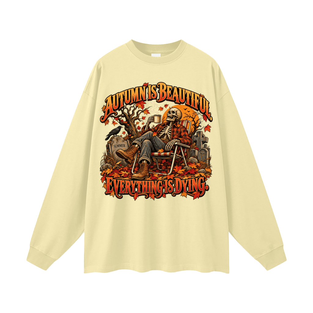 Pale yellow Autumn Is Beautiful long-sleeve T-shirt, front view with a seated skeleton, fall leaves and orange lettering.