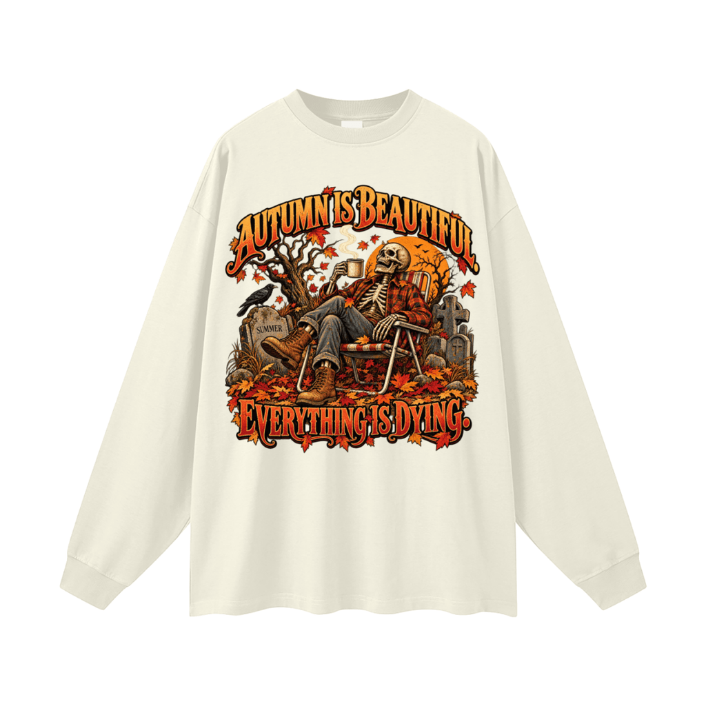 Ivory Autumn Is Beautiful long-sleeve T-shirt, front view with a seated skeleton, fall leaves and orange lettering.