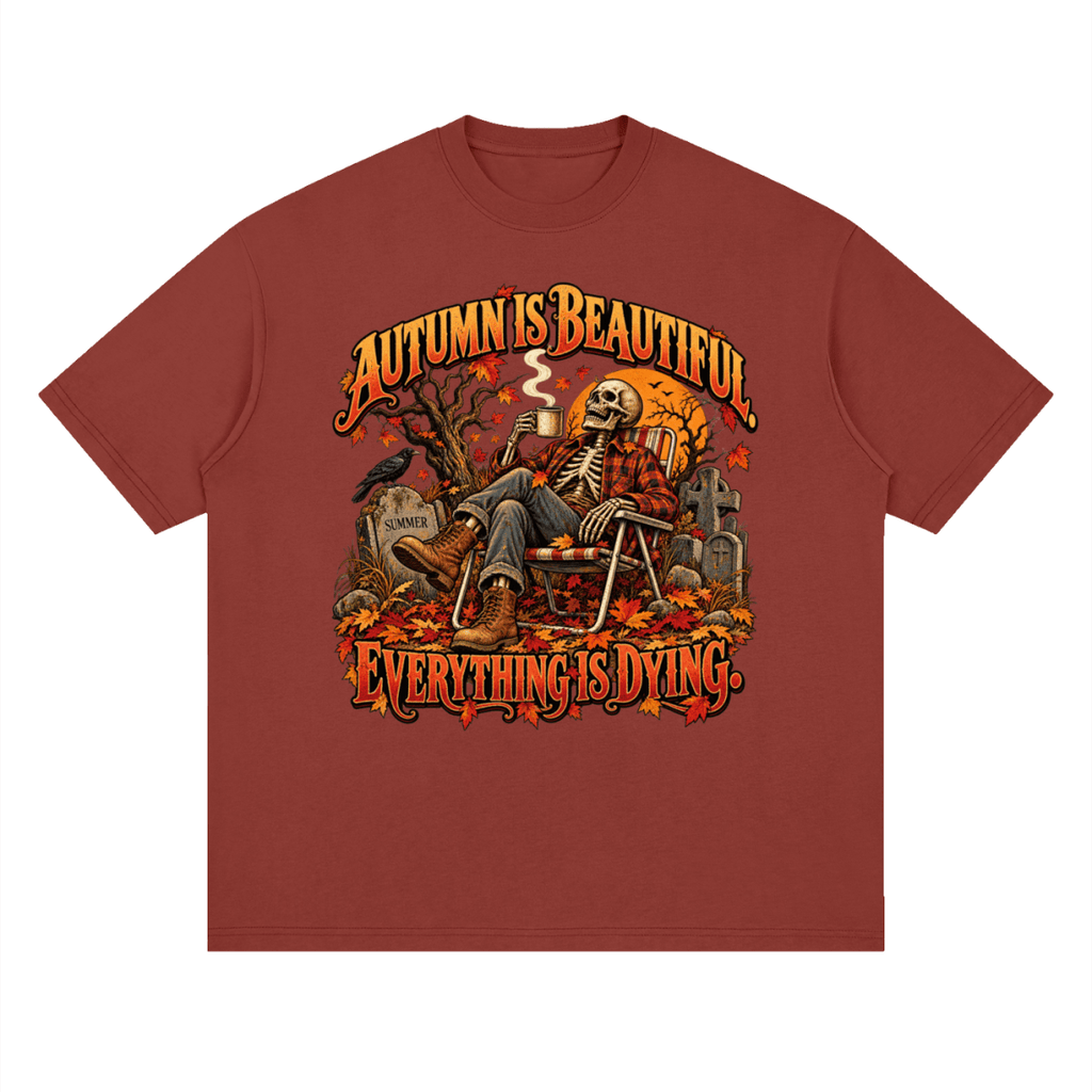 Rust red Autumn Is Beautiful drop-shoulder T-shirt, front view with a seated skeleton, fall leaves and orange lettering.