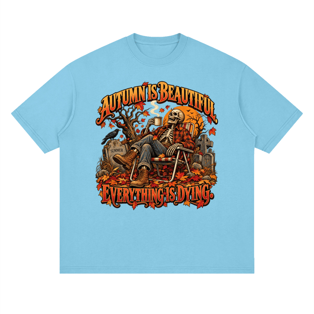 Bright blue Autumn Is Beautiful drop-shoulder T-shirt, front view with a seated skeleton, fall leaves and orange lettering.