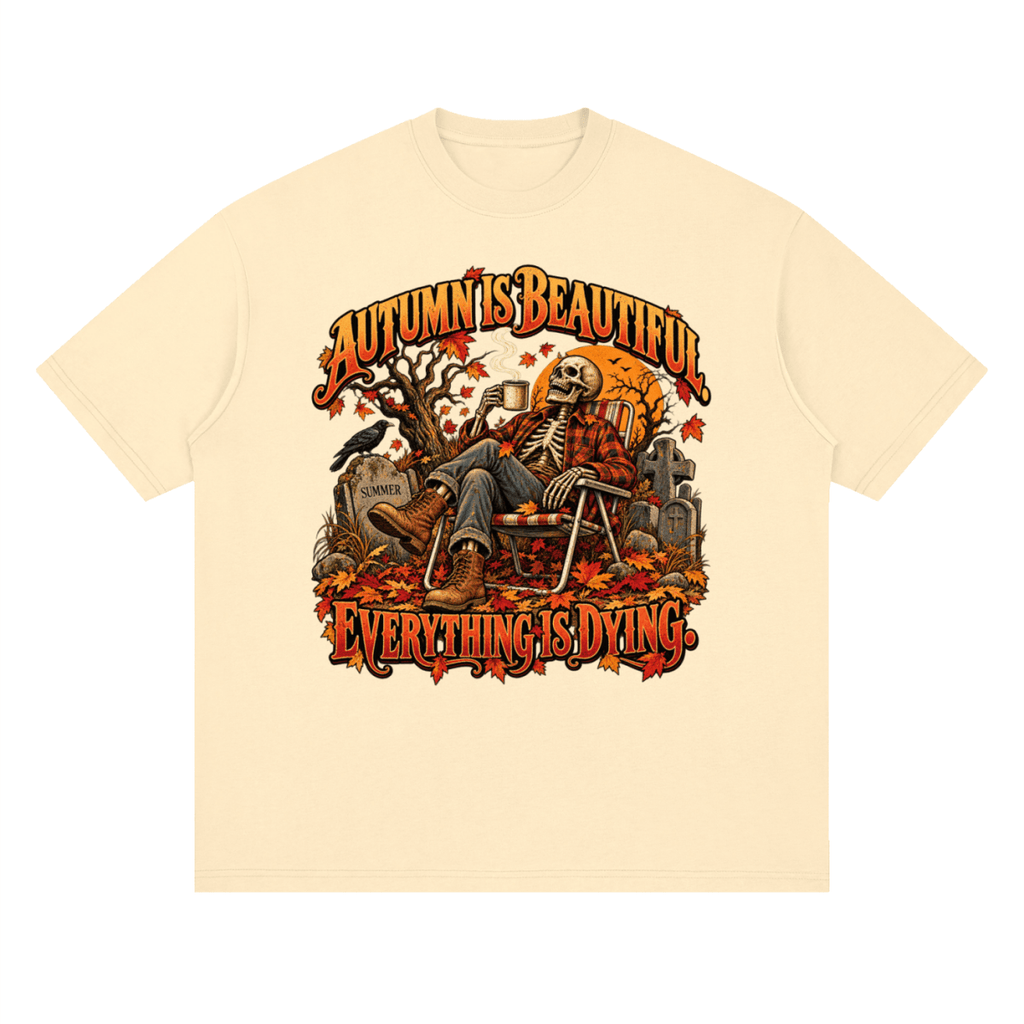 Pale yellow Autumn Is Beautiful drop-shoulder T-shirt, front view with a seated skeleton, fall leaves and orange lettering.