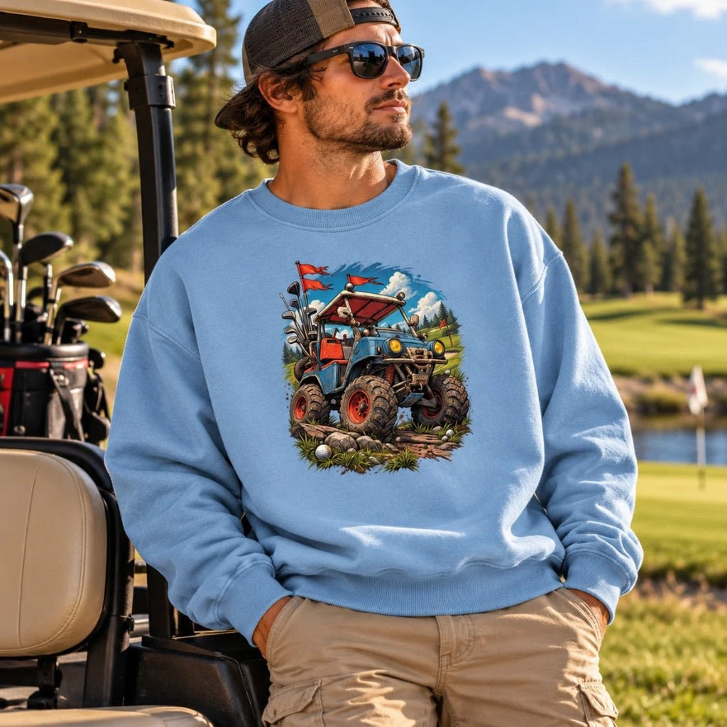 Model wearing a light blue Battle-Hardened Golf Cart sweatshirt beside a golf cart with mountains behind.