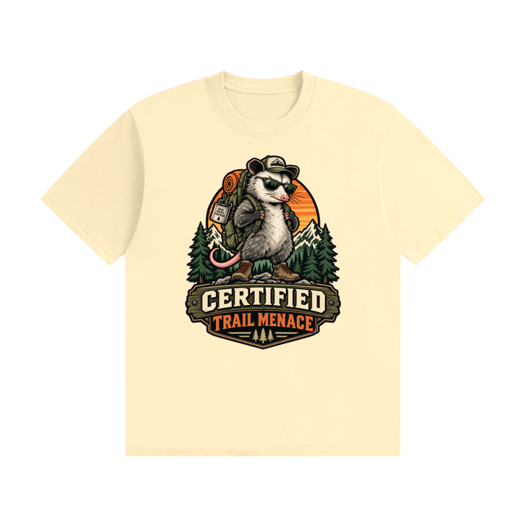Cream cotton T-shirt, front view with a hiking possum with sunglasses and backpack against mountains and an orange sunset.