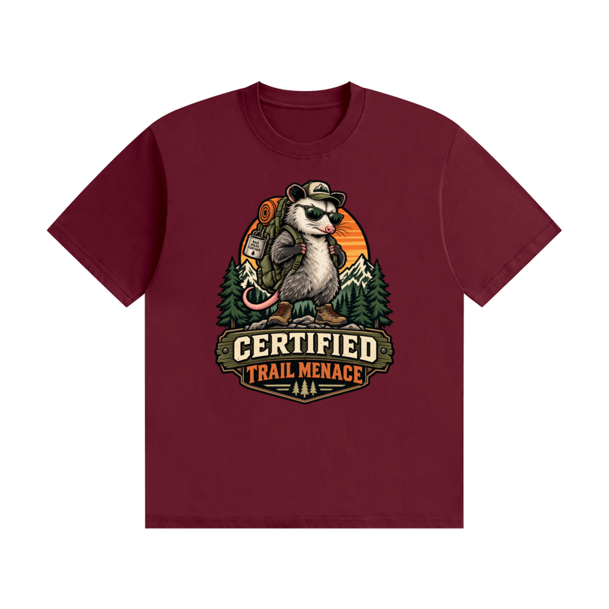 Burgundy cotton T-shirt, front view with a hiking possum with sunglasses and backpack against mountains and an orange sunset.