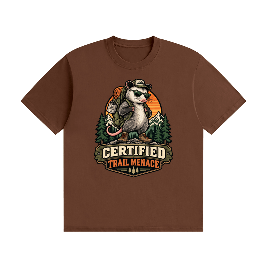 Brown cotton T-shirt, front view with a hiking possum with sunglasses and backpack against mountains and an orange sunset.