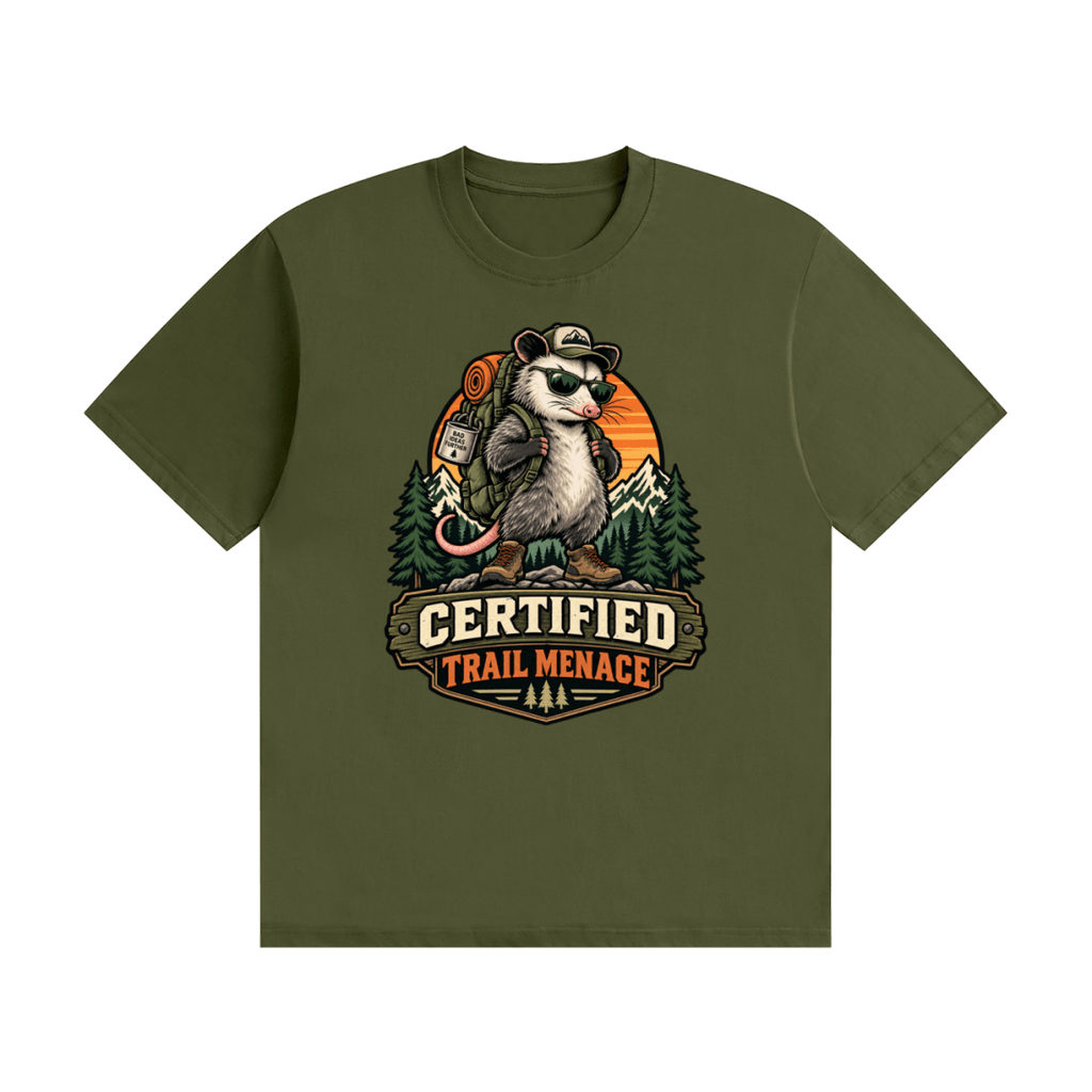 Olive green cotton T-shirt, front view with a hiking possum with sunglasses and backpack against mountains and an orange sunset.