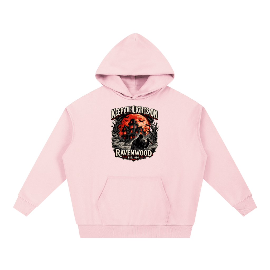 Pink heavyweight hoodie, front view with a haunted house, orange moon and knife-holding silhouette with Keep the Lights On and Ravenwood Est. 1986 lettering.