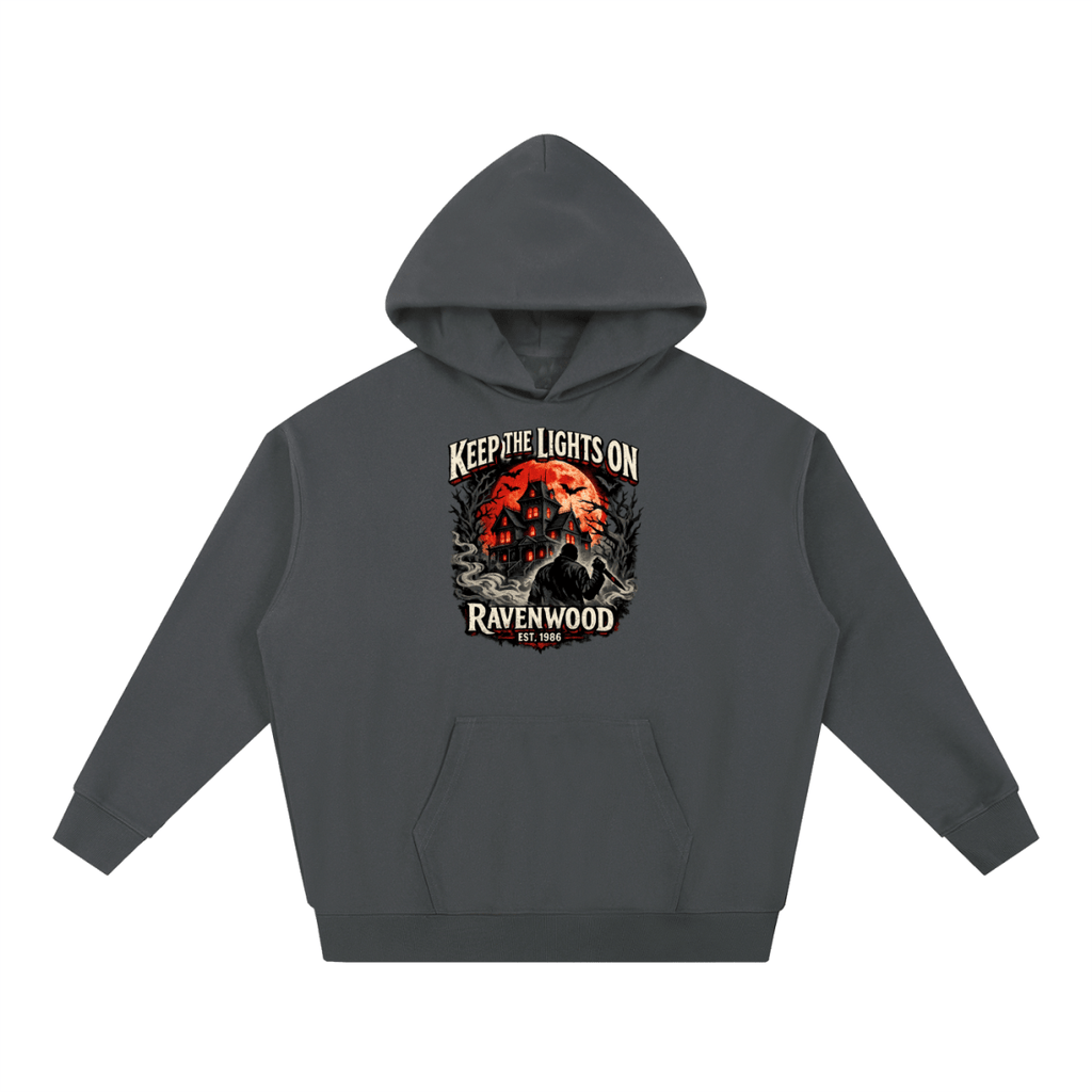 Charcoal heavyweight hoodie, front view with a haunted house, orange moon and knife-holding silhouette with Keep the Lights On and Ravenwood Est. 1986 lettering.