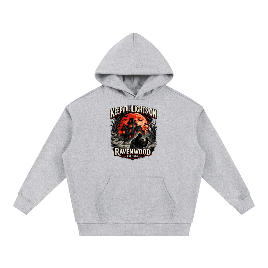 Heather gray heavyweight hoodie, front view with a haunted house, orange moon and knife-holding silhouette with Keep the Lights On and Ravenwood Est. 1986 lettering.