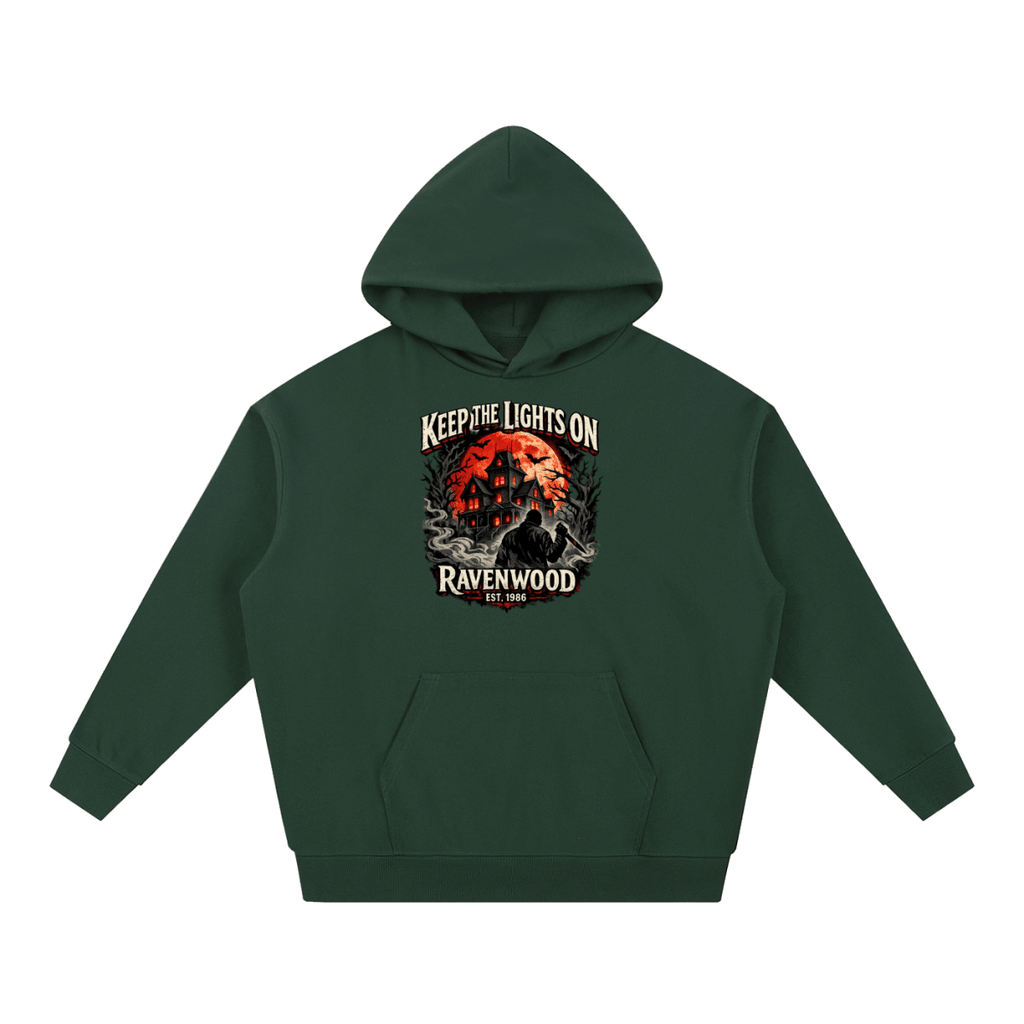 Forest green heavyweight hoodie, front view with a haunted house, orange moon and knife-holding silhouette with Keep the Lights On and Ravenwood Est. 1986 lettering.