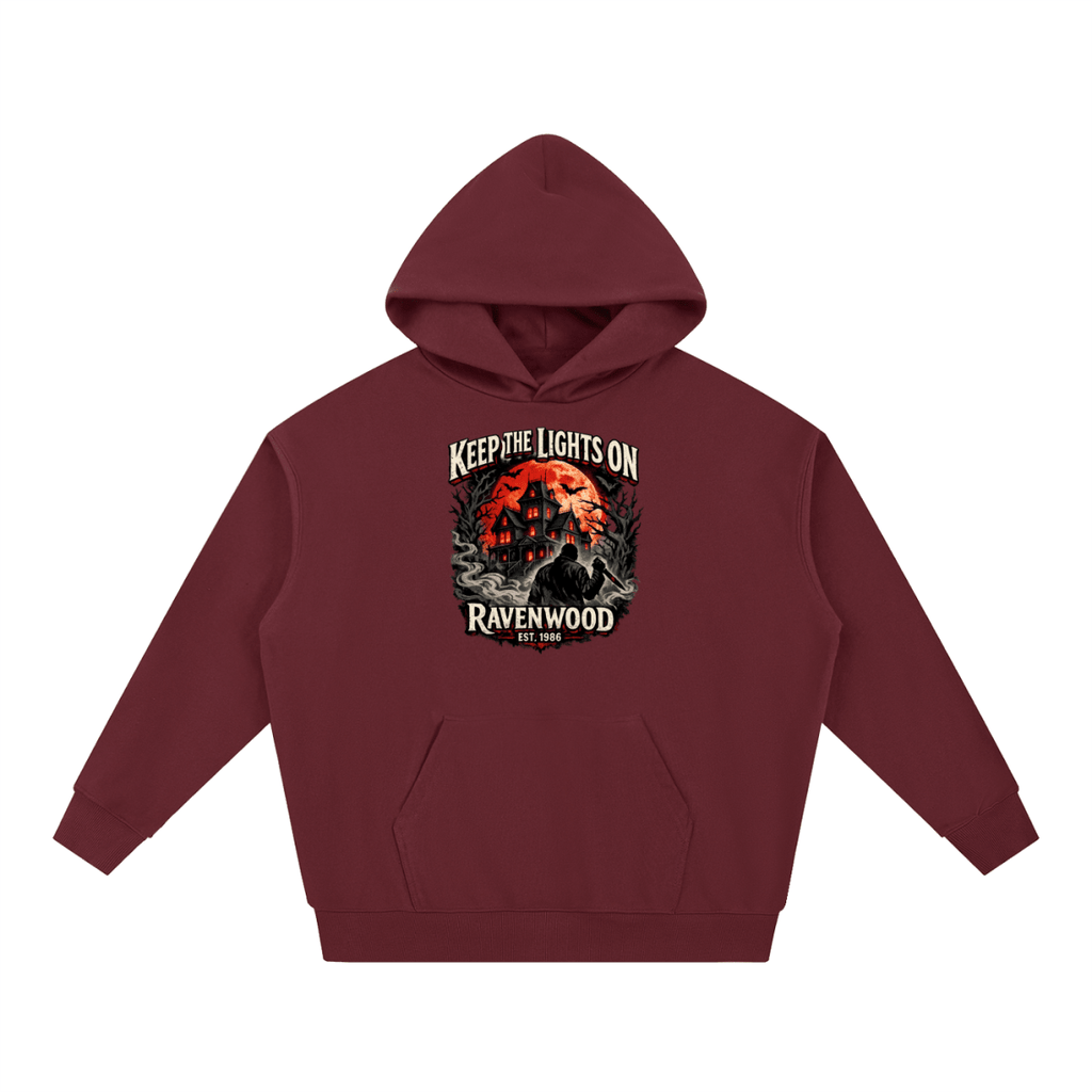 Burgundy heavyweight hoodie, front view with a haunted house, orange moon and knife-holding silhouette with Keep the Lights On and Ravenwood Est. 1986 lettering.