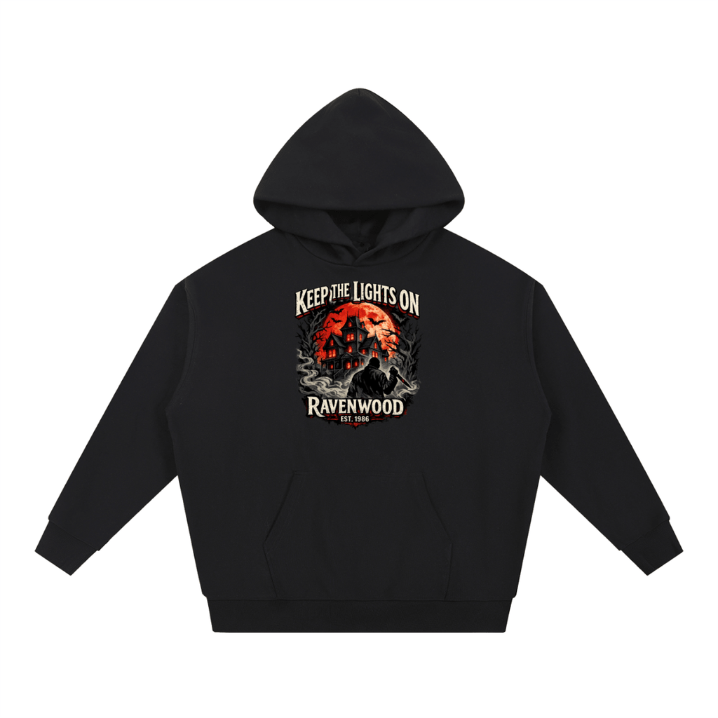 Black heavyweight hoodie, front view with a haunted house, orange moon and knife-holding silhouette with Keep the Lights On and Ravenwood Est. 1986 lettering.