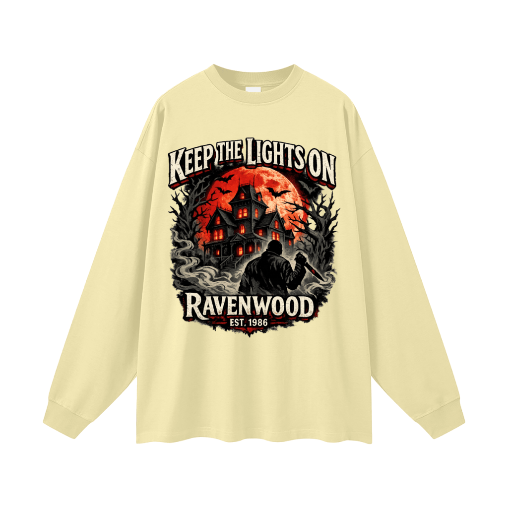 Pale yellow oversized long-sleeve T-shirt, front view with a haunted house, orange moon and knife-holding silhouette with Keep the Lights On and Ravenwood Est. 1986 lettering.