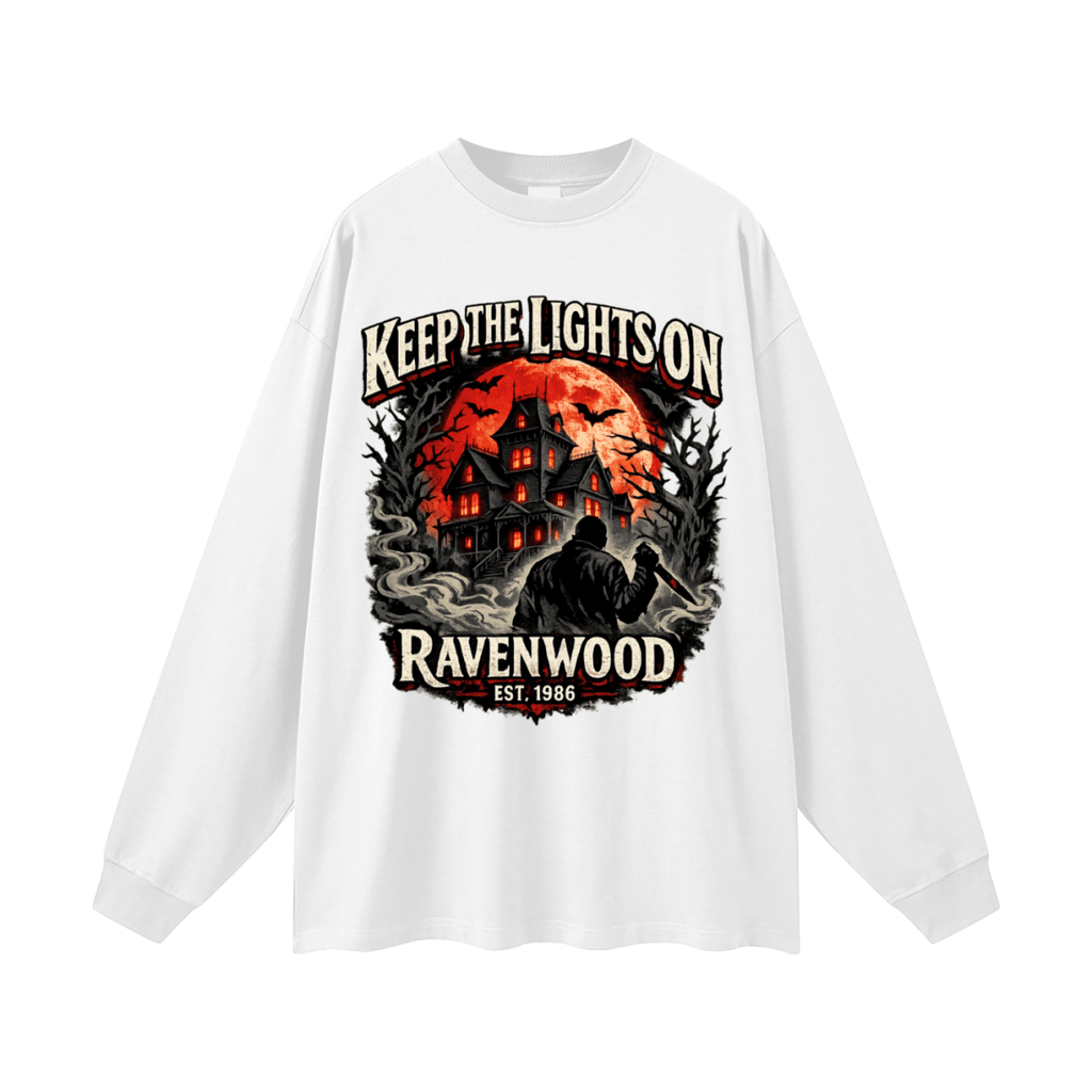 White oversized long-sleeve T-shirt, front view with a haunted house, orange moon and knife-holding silhouette with Keep the Lights On and Ravenwood Est. 1986 lettering.