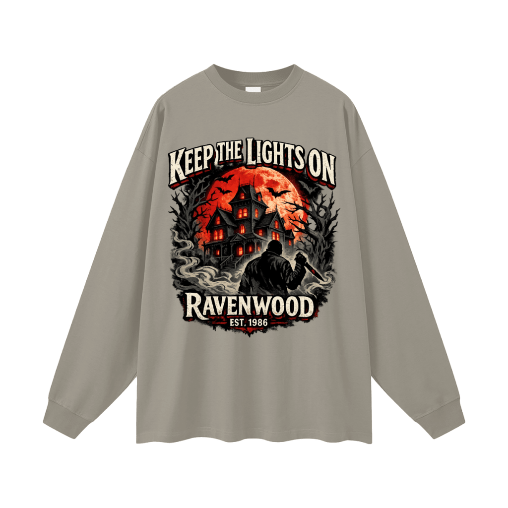 Gray oversized long-sleeve T-shirt, front view with a haunted house, orange moon and knife-holding silhouette with Keep the Lights On and Ravenwood Est. 1986 lettering.