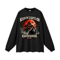 Black oversized long-sleeve T-shirt, front view with a haunted house, orange moon and knife-holding silhouette with Keep the Lights On and Ravenwood Est. 1986 lettering.