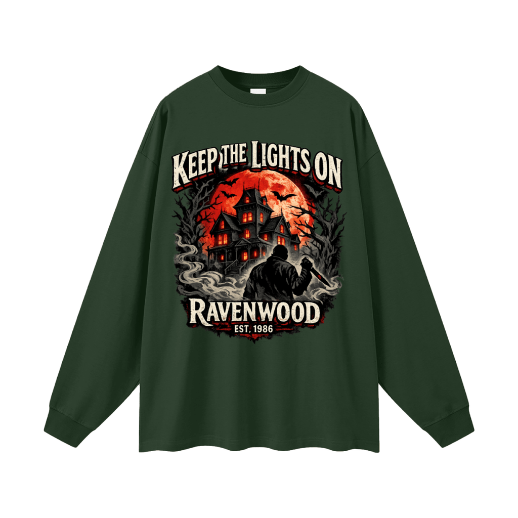 Forest green oversized long-sleeve T-shirt, front view with a haunted house, orange moon and knife-holding silhouette with Keep the Lights On and Ravenwood Est. 1986 lettering.