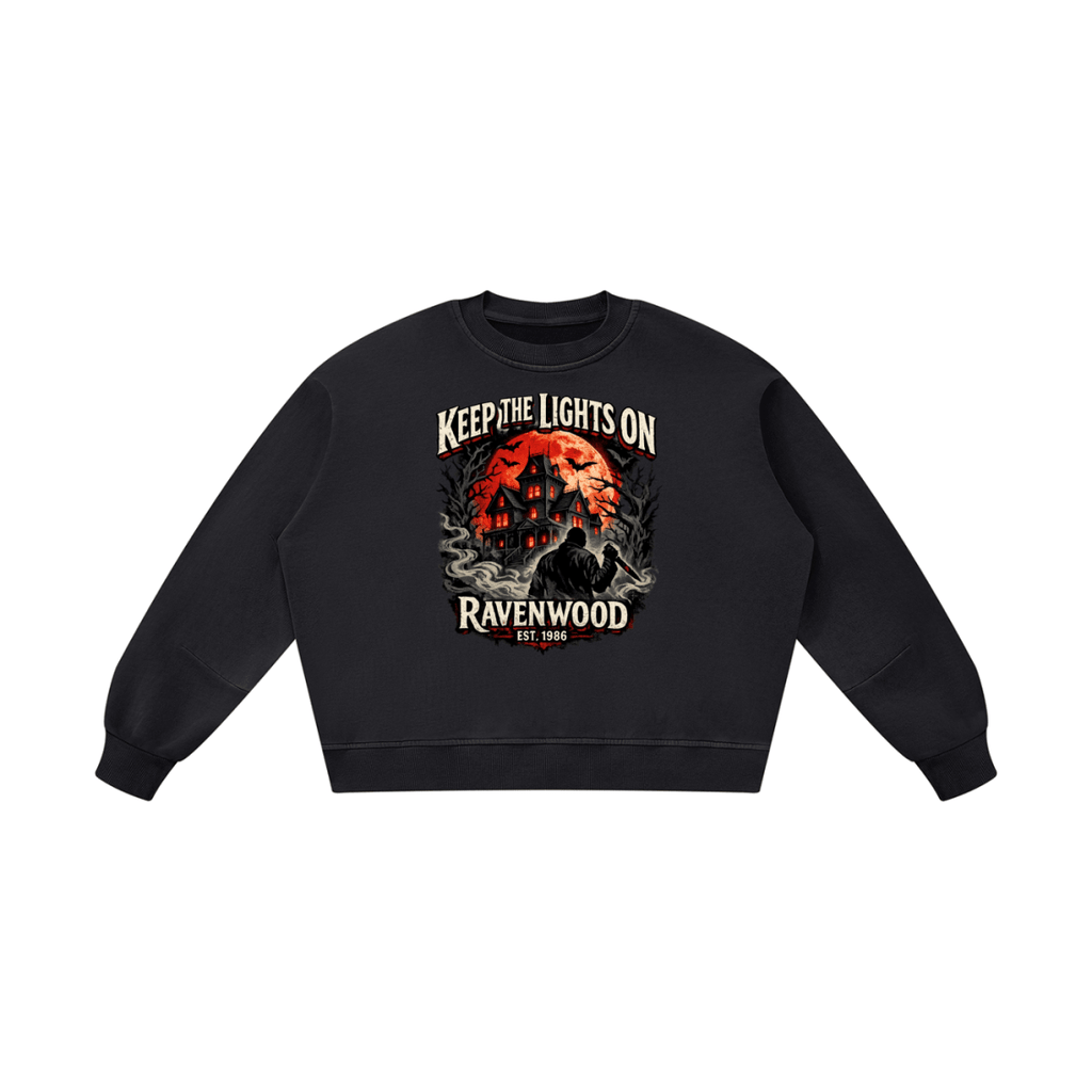 Black boxy vintage-washed sweatshirt, front view with a haunted house, orange moon and knife-holding silhouette with Keep the Lights On and Ravenwood Est. 1986 lettering.