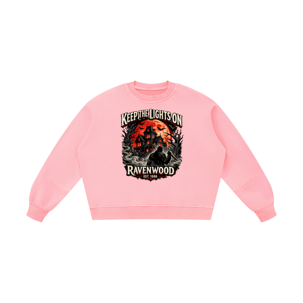 Pink boxy vintage-washed sweatshirt, front view with a haunted house, orange moon and knife-holding silhouette with Keep the Lights On and Ravenwood Est. 1986 lettering.