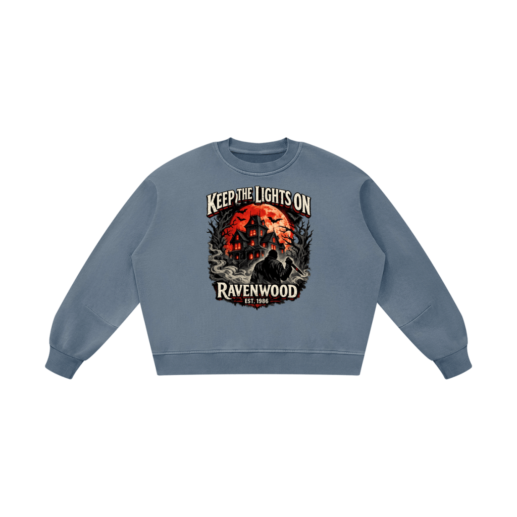 Blue gray boxy vintage-washed sweatshirt, front view with a haunted house, orange moon and knife-holding silhouette with Keep the Lights On and Ravenwood Est. 1986 lettering.