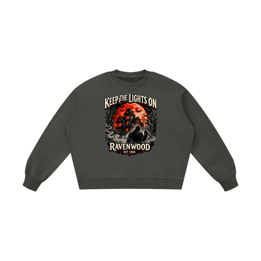 Dark gray boxy vintage-washed sweatshirt, front view with a haunted house, orange moon and knife-holding silhouette with Keep the Lights On and Ravenwood Est. 1986 lettering.