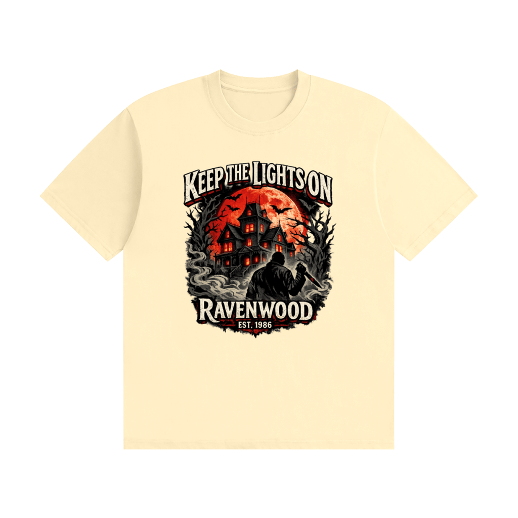 Cream cotton T-shirt, front view with a haunted house, orange moon and knife-holding silhouette with Keep the Lights On and Ravenwood Est. 1986 lettering.