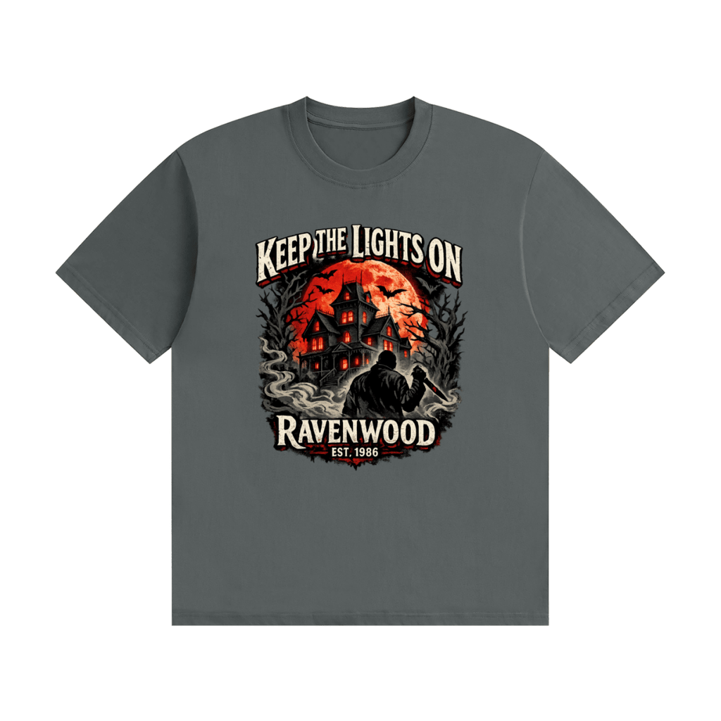 Dark gray cotton T-shirt, front view with a haunted house, orange moon and knife-holding silhouette with Keep the Lights On and Ravenwood Est. 1986 lettering.