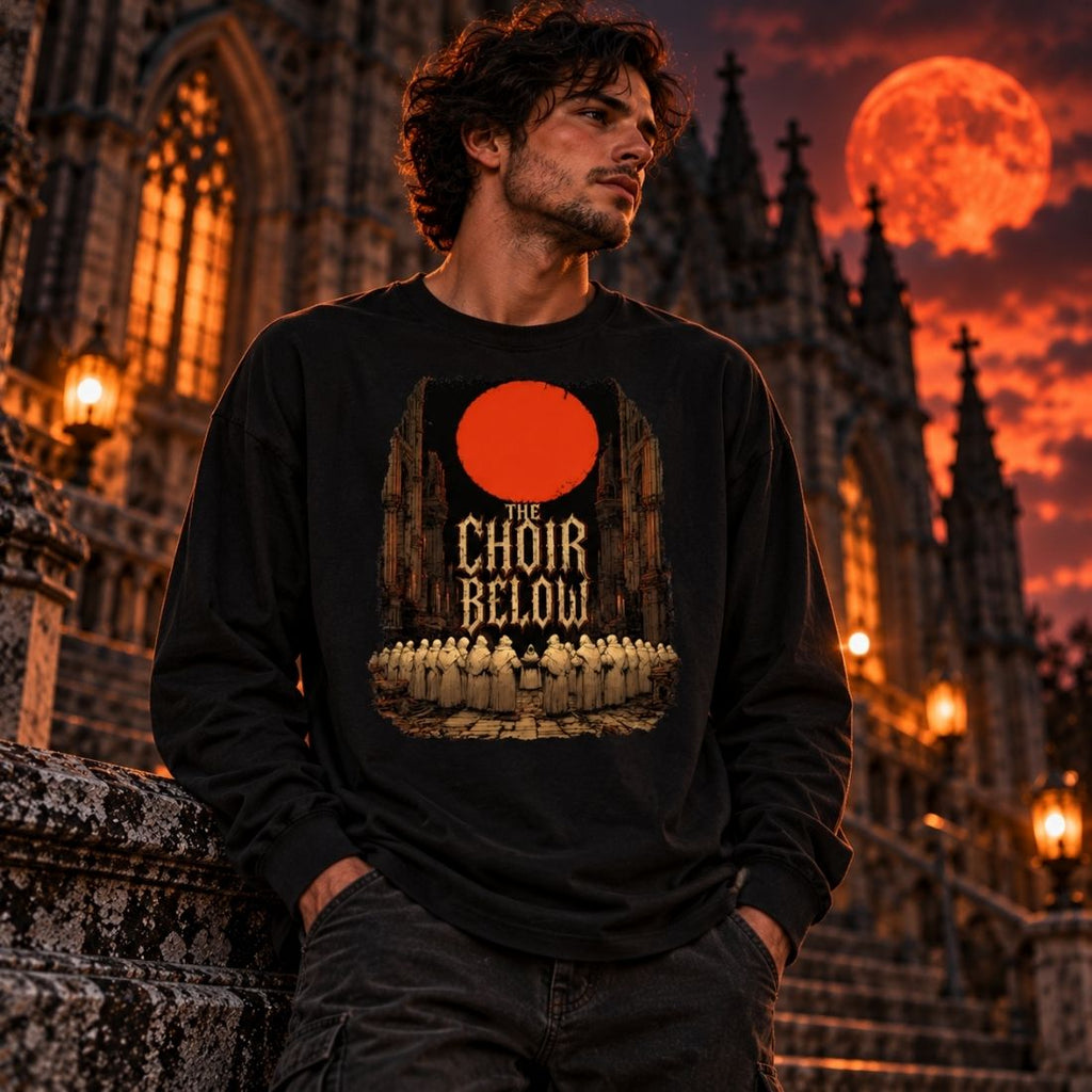 Model wearing a black The Choir Below long-sleeve T-shirt beside a Gothic building with an orange moon behind.