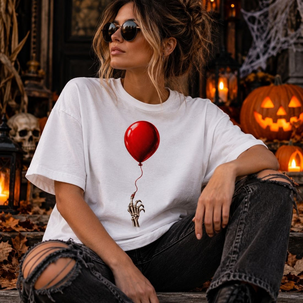 Model wearing a white The Last Balloon T-shirt, sunglasses and ripped dark jeans, seated among pumpkins and Halloween decorations.