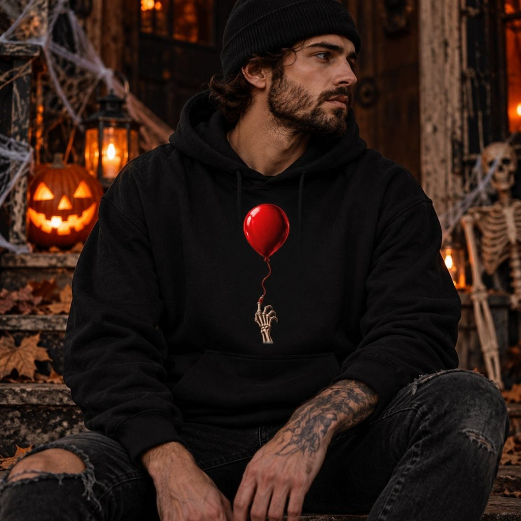 Model wearing a black The Last Balloon hoodie, ripped dark jeans and a beanie, seated among jack-o'-lanterns and Halloween decorations.