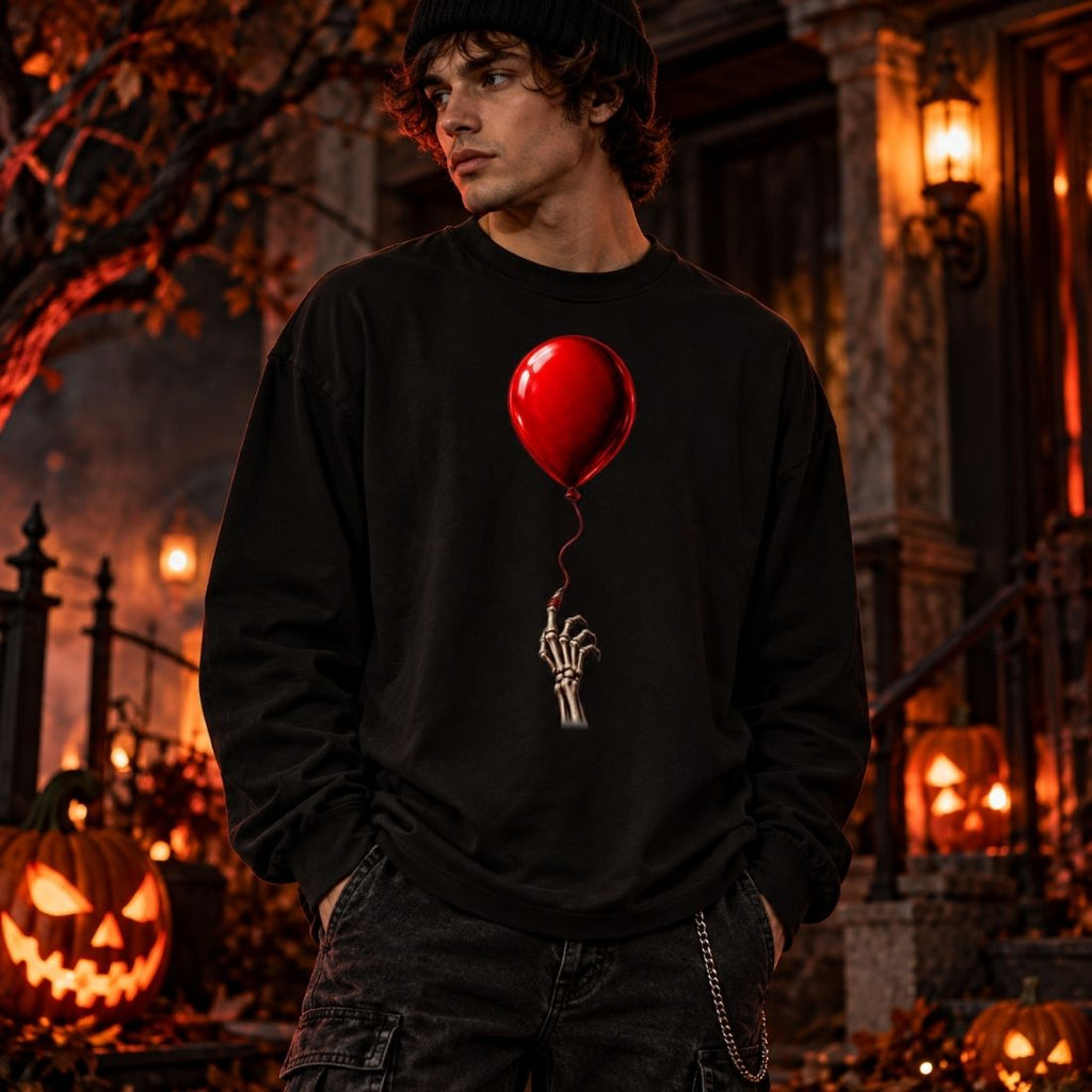 Model wearing a black The Last Balloon long sleeve T-shirt and dark pants outside a house with glowing jack-o'-lanterns.